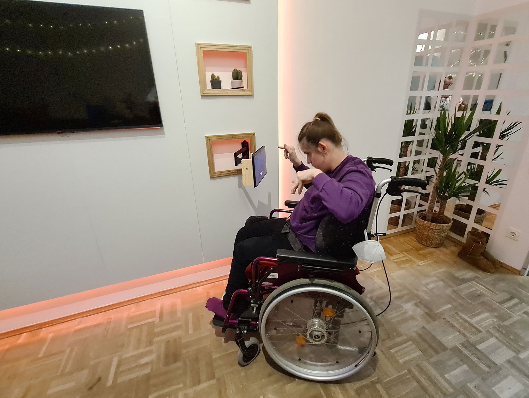 Ein Mädchen im Rollstuhl bedient ein an der Wand befestigtes Tablet