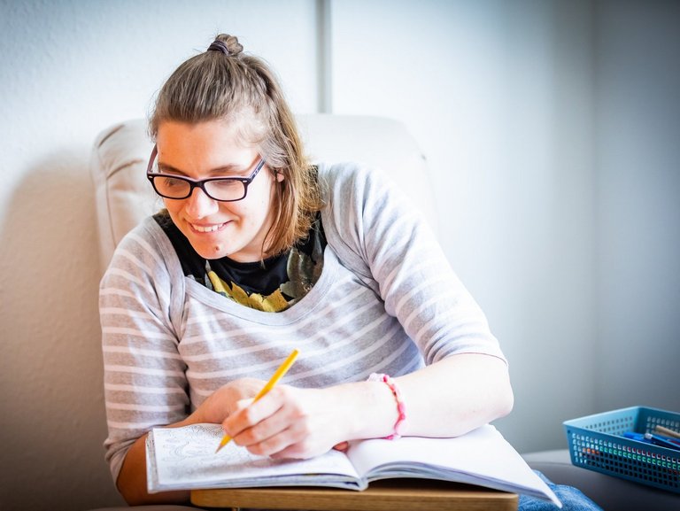 Eine Bewohnerin in ihrem Zimmer schreibt in ein Buch
