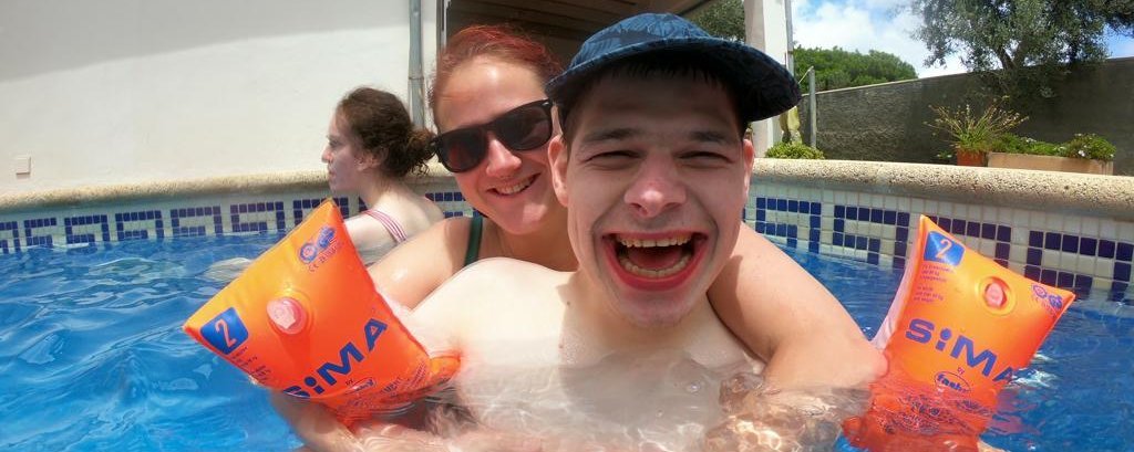 Betreuerin und junge mit Behinderung haben Spaß im Schwimmbad