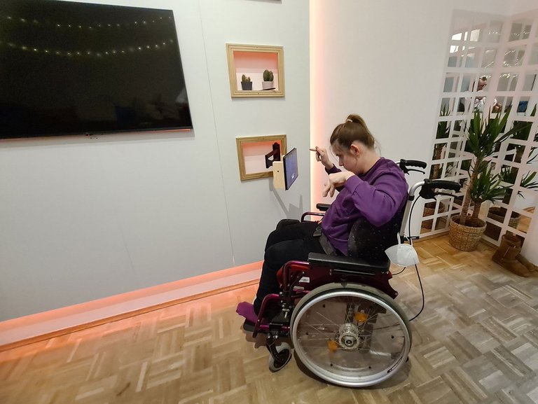 Ein Mädchen im Rollstuhl bedient ein an der Wand befestigtes Tablet
