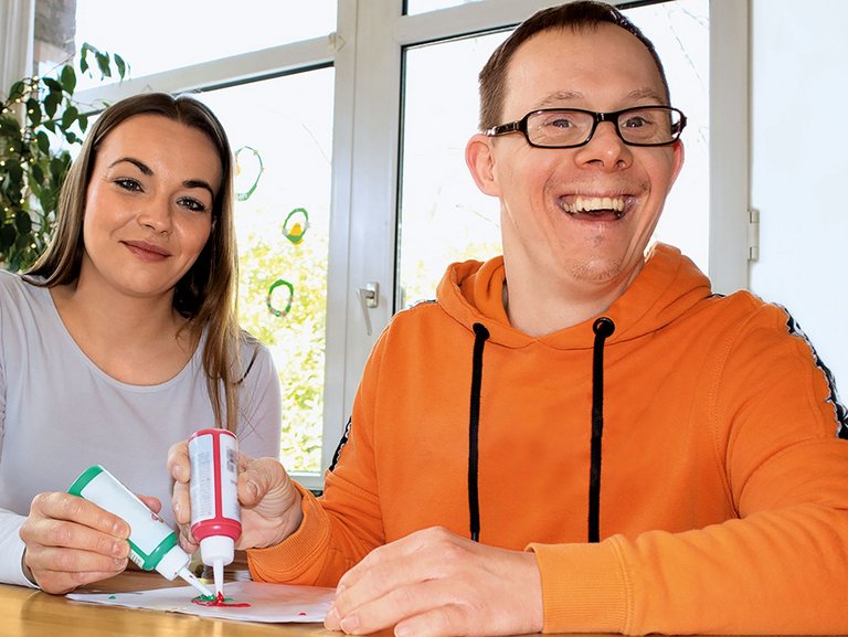 Eine Junge Frau malt mit einem Mann ein Bild mit bunten Farben